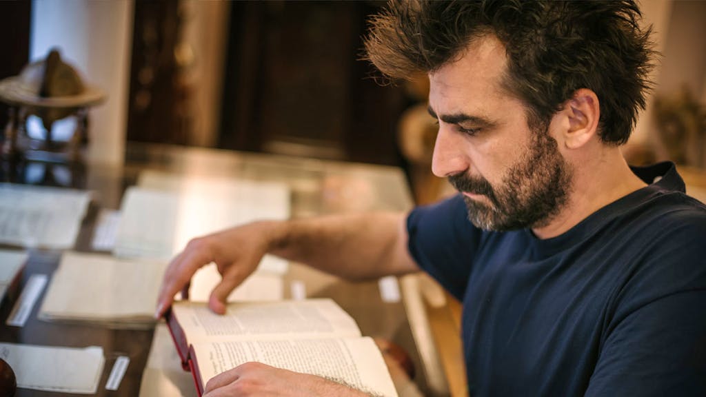 Jewish man reading the New Testament in the library