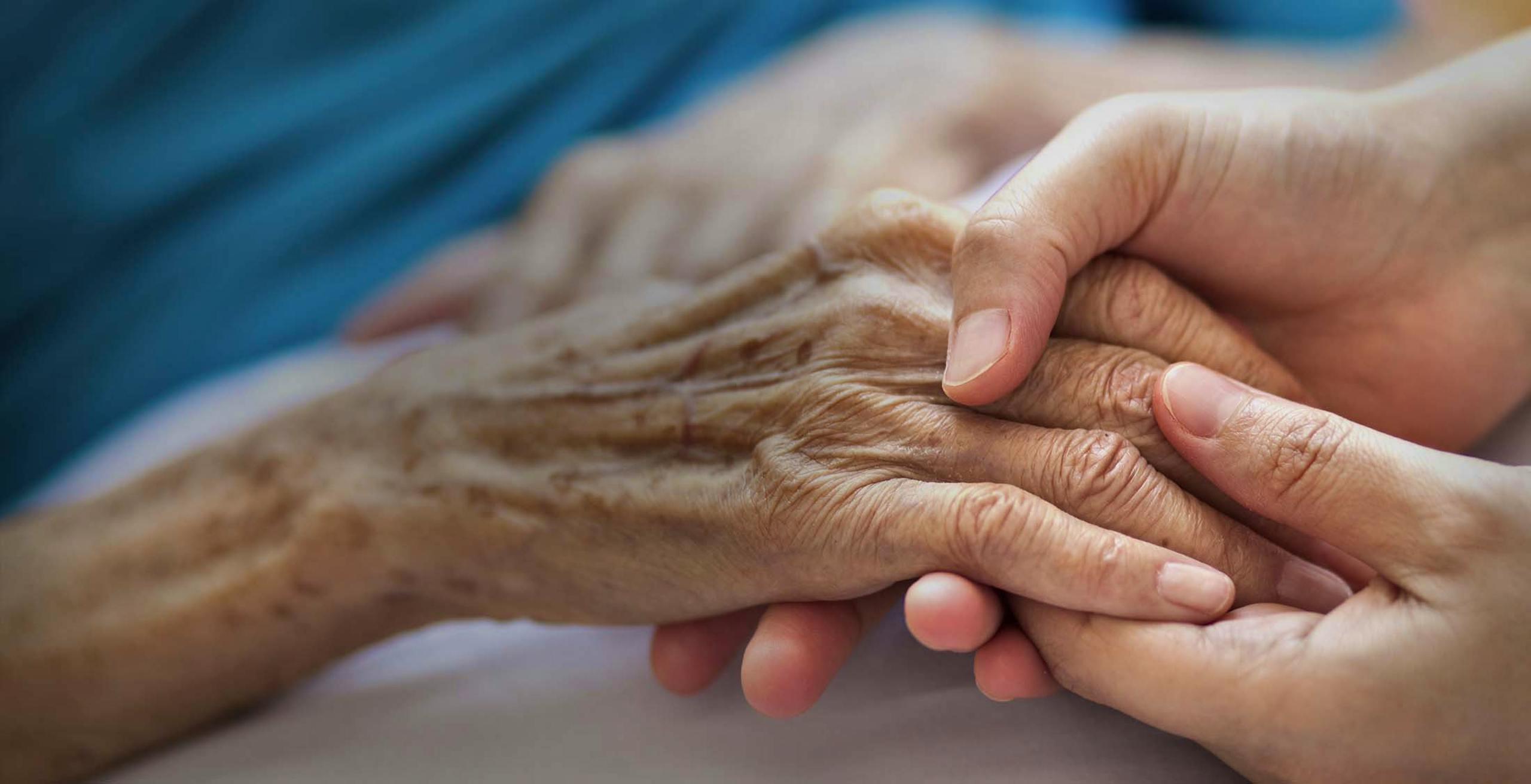 Woman holding elderly woman's hand in a hospital