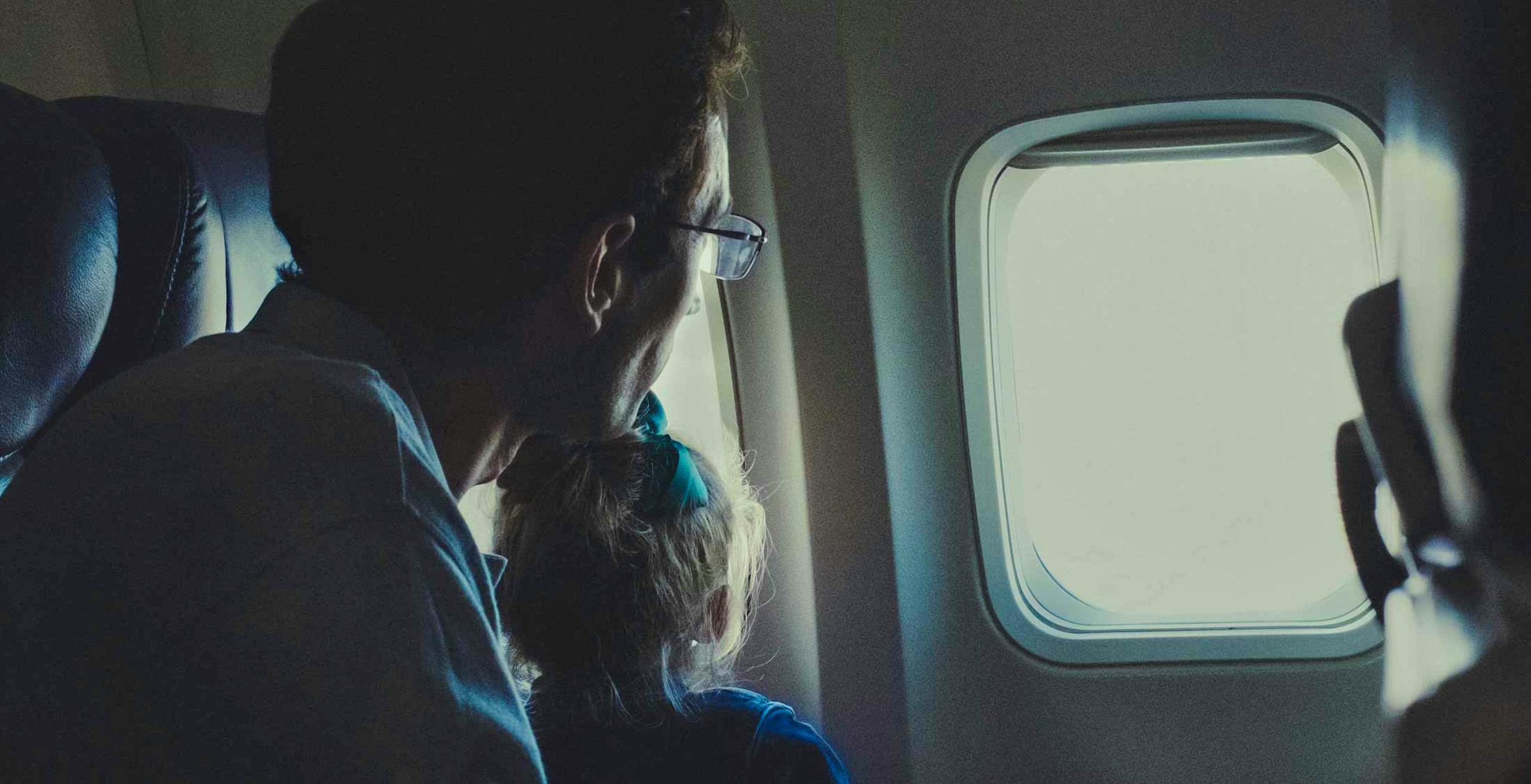 Jewish father and son looking out the window of an airplane.