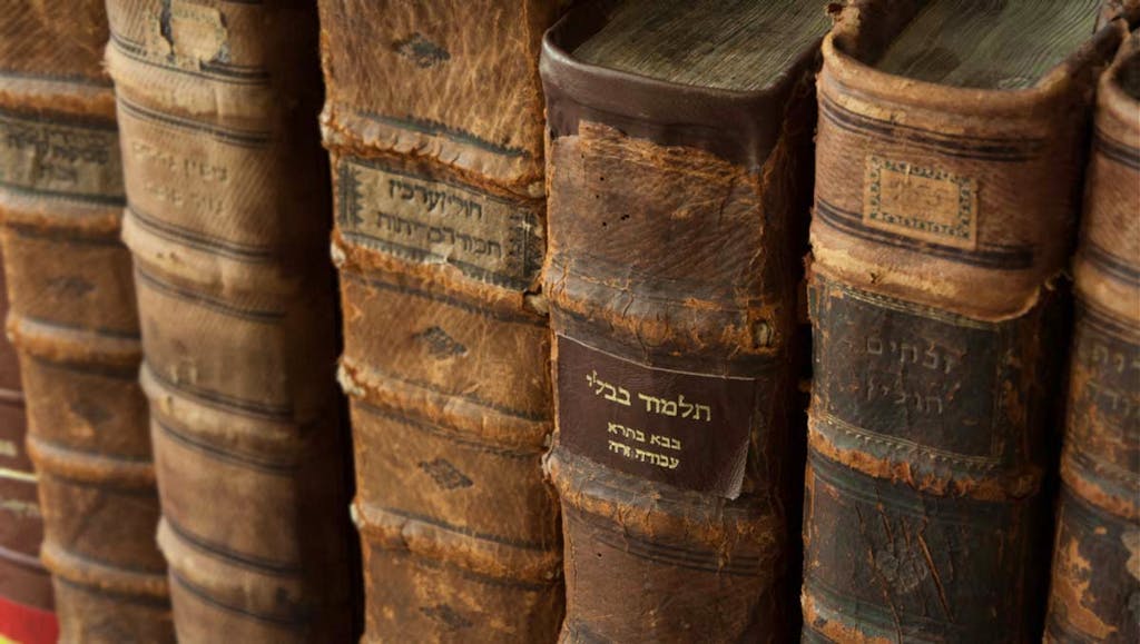 An old copy of the Talmud on a shelf with other Jewish books